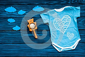Newborn baby`s sleep concept. To put the child to bed. Baby bodysuit near clouds on blue wooden background top view copy
