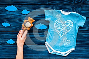 Newborn baby`s sleep concept. To put the child to bed. Baby bodysuit near clouds and cbaby accessories on blue wooden