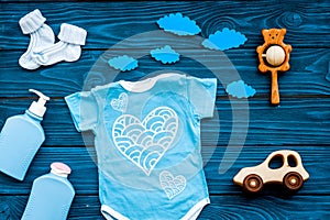 Newborn baby`s sleep concept. To put the child to bed. Baby bodysuit near clouds and cbaby accessories on blue wooden