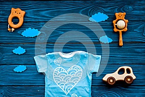 Newborn baby`s sleep concept. To put the child to bed. Baby bodysuit near clouds and cbaby accessories on blue wooden