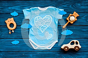 Newborn baby`s sleep concept. To put the child to bed. Baby bodysuit near clouds and cbaby accessories on blue wooden