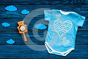 Newborn baby`s sleep concept. To put the child to bed. Baby bodysuit near clouds and cbaby accessories on blue wooden