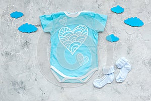 Newborn baby`s sleep concept. To put the child to bed. Baby bodysuit near clouds on grey background top view