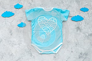 Newborn baby`s sleep concept. To put the child to bed. Baby bodysuit near clouds on grey background top view