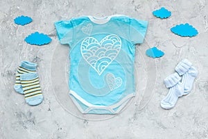 Newborn baby`s sleep concept. To put the child to bed. Baby bodysuit near clouds on grey background top view