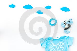 Newborn baby`s sleep concept. To put the child to bed. Baby bodysuit near clouds on white background top view copy space