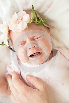 Newborn baby screaming in pain with colic with mother`s hand on