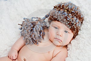 Newborn baby without shirt and wearing knitted hat