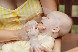 Newborn Baby Skin Care. Close up Mother holding newborn baby in hands on nature background. Outdoor portrait of mother