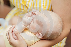 Newborn Baby Skin Care. Close up Mother holding newborn baby in hands on nature background. Outdoor portrait of mother