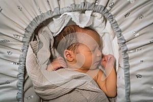 Newborn baby sleep first days of life. Cute little newborn child sleeping peacefully in cradle with pillows, protected and serene