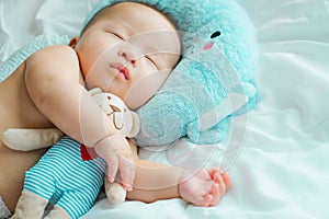 Newborn baby sleep witha doll on the bed,Cute little Asian 5 months sleeping in bed while hugging bear, Daytime sleep