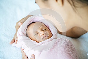 The newborn baby sleeping in the arms of the mother