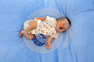 Newborn baby sleeping on blue fur fabric bed.