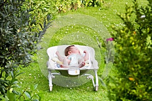 Newborn baby sleeping in a bouncer in the garden