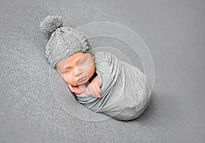 Newborn baby sleeping curled up in grey blanket photo