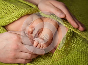 Newborn Baby Sleeping in Father Hands, Parent Protecting New Born Child, one month Child Sleep under Green Woolen Blanket