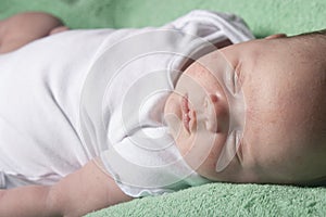 Newborn baby sleeping on a green blanket