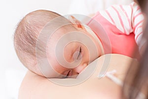 Newborn baby sleeping in mother breast. Adorable infant kid. Child and mom closeness.