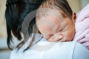 Newborn baby sleeping on the mother`s shoulder