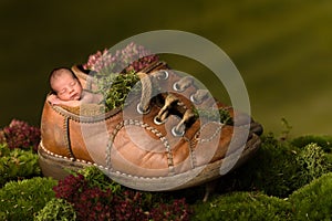 Newborn baby sleeping in old brown shoes