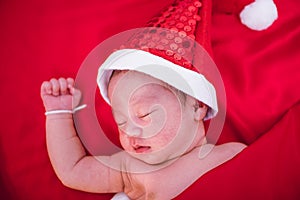 Newborn baby sleeping on santa het and red background