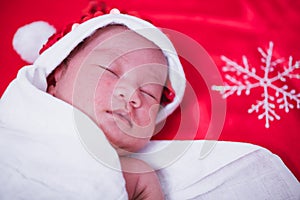 Newborn baby sleeping on santa het and red background,