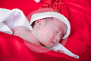 Newborn baby sleeping on santa het and red background