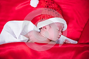 Newborn baby sleeping on santa het and red background