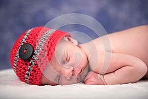 Newborn baby sleeping on a white blanket.