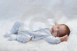 Newborn baby sleeping on white fur in sunlight