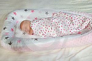 Newborn baby sleeping wrapped in blanket.