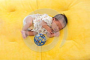 Newborn baby sleeping on yellow fur fabric bed.