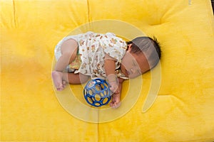 Newborn baby sleeping on yellow fur fabric bed.