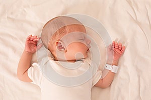 The newborn baby sleeps on the bed in the maternity hospital