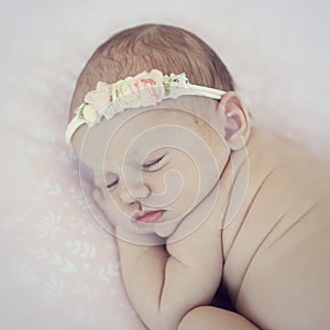 Newborn baby sleeps on blanket. Time to sleep for infant. Hairy toddler girl with flower pink headband