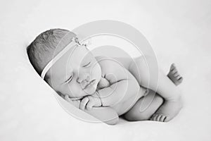 Newborn baby sleeps on blanket. Time to sleep for infant. Hairy toddler girl with flower pink headband