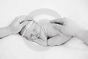 Newborn baby sleeps on blanket. Time to sleep for infant. Hairy toddler girl with flower pink headband. Parents hands