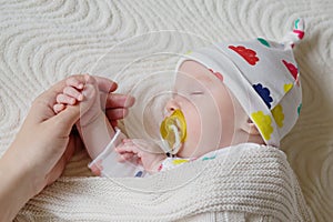 Newborn baby sleeps with caring touch of mother`s hands