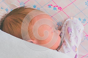 A newborn baby sleeps sweetly on its side, throwing a handle covered with a blanket. View from above