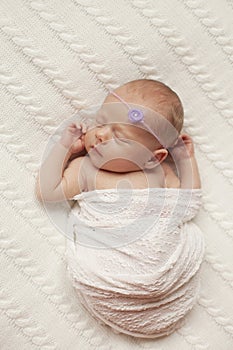 A newborn baby sleeps on a white plaid