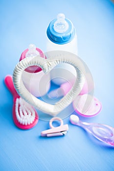 Newborn baby story. Children's toys, scissors, baby bottle, nipple, hairbrush on blue background