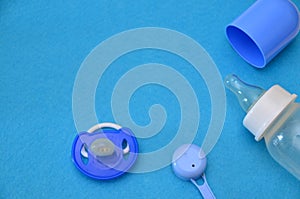 Newborn baby story. Children's toys, scissors, baby bottle, nipple, hairbrush on blue background. pacifier, toys