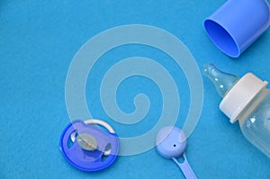 Newborn baby story. Children's toys, scissors, baby bottle, nipple, hairbrush on blue background. pacifier, toys