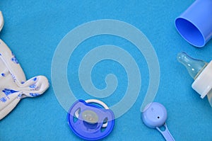 Newborn baby story. Children's toys, scissors, baby bottle, nipple, hairbrush on blue background. pacifier, toys