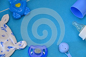 Newborn baby story. Children's toys, scissors, baby bottle, nipple, hairbrush on blue background. pacifier, toys