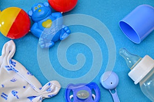 Newborn baby story. Children's toys, scissors, baby bottle, nipple, hairbrush on blue background. pacifier, toys