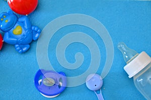 Newborn baby story. Children's toys, scissors, baby bottle, nipple, hairbrush on blue background. pacifier, toys