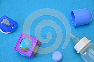 Newborn baby story. Children's toys, scissors, baby bottle, nipple, hairbrush on blue background. pacifier, toys