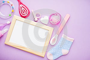 Newborn baby story. Frame with copyspace and children's toys, scissors, baby bottle, nipple, hairbrush on violet background